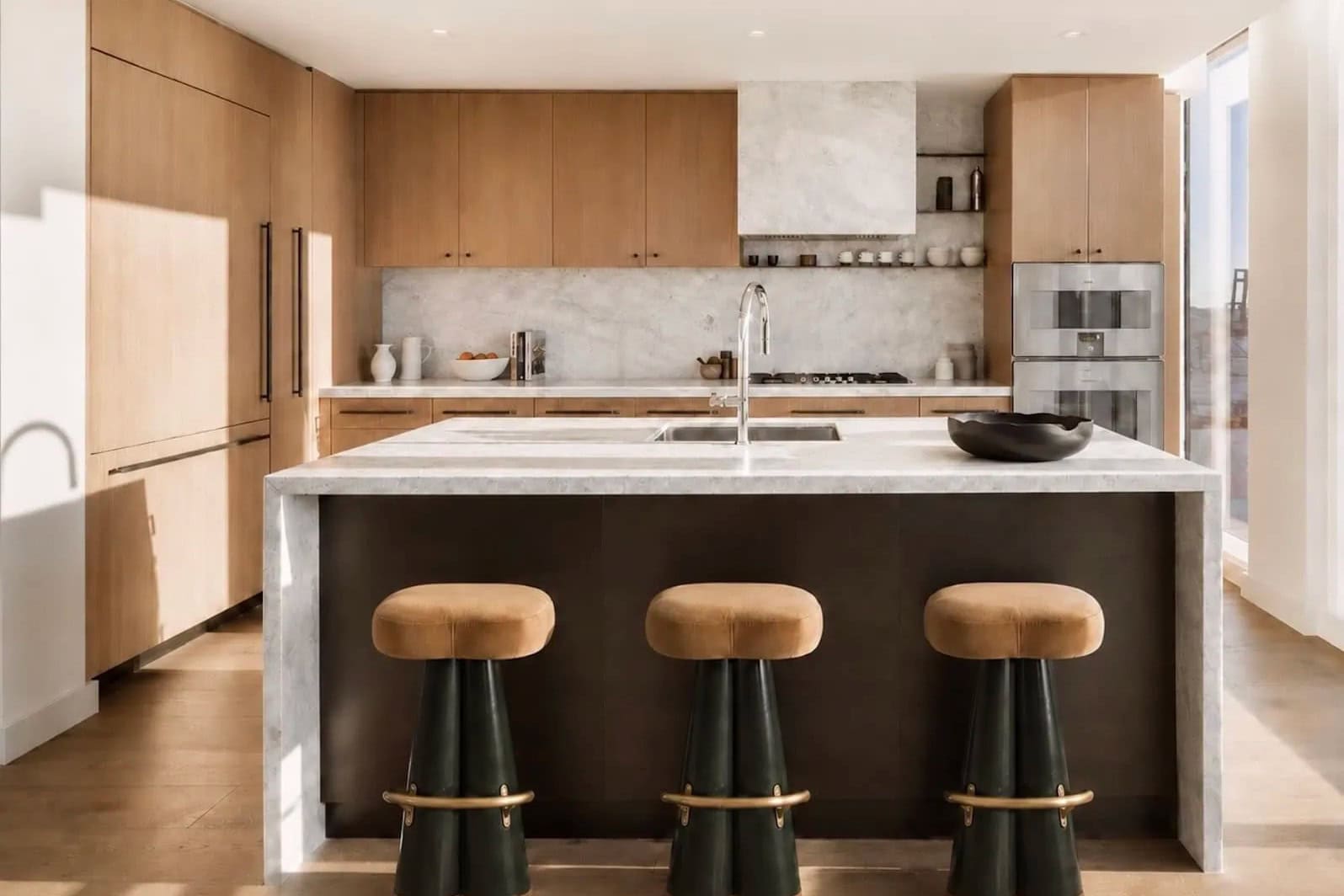 Kitchen with white oak cabinetry, a marble waterfall island and leather counter stools in a Brooklyn tower.